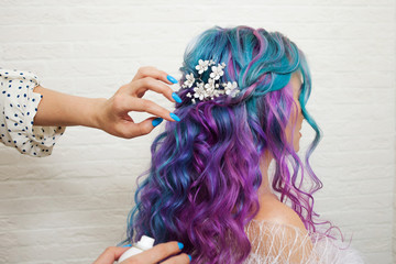 hair stylist doing styling on long curls. Bright multi-colored hair coloring