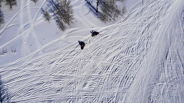 Drone Circles Around Family As They Are Riding Skimobile In Forest. Excellent view of snowmobile tracks shot by drawn. You can see in this video 2 snow scooters as well.