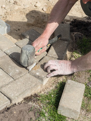 The worker lay the paving brick with special hammers