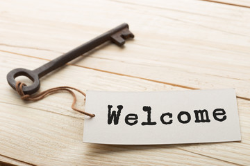 VIntage hotel key with welcome tag on the wooden background