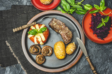 grilled autumn dinner, steak, baked tomato with cheese, baked potatoes with garlic and mushrooms