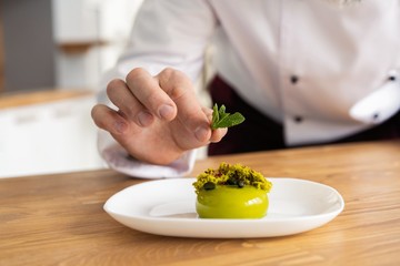 Close up pastry chef decoration delicious dessert dish, serving for customers in bakery, garnishing dessert plate in commercial kitchen.