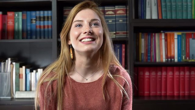 Pretty girl with adorable smile looking on camera in library room