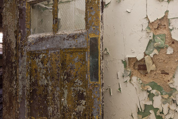 Last remnants of yellow door left open with peeling paint in an abandoned school