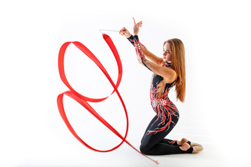 Rhythmic gymnastics. Young gymnast girl with red ribbon on white background