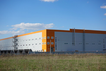 Fototapeta na wymiar Industrial building, warehouse. Blue sky with clouds.
