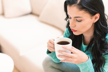 Young woman drinking coffee in her home