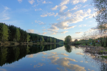 Fototapeta premium Beautiful sunset on the forest lake. Clouds reflected in water.