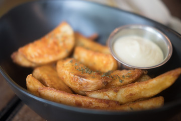Potato wedges in small bowl with sour cream