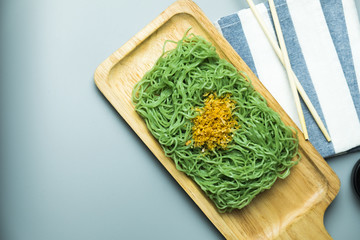 Green noodles with fried garlic on wooden tray