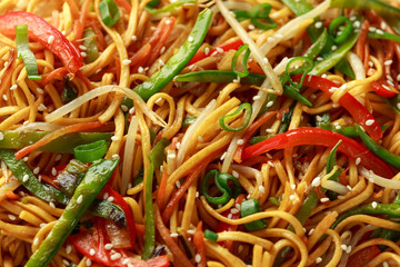 Chow mein, noodles and vegetables dish with wooden chopsticks