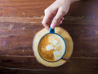 Hand holding hot latte art coffee cup