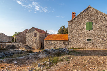 Fototapeta na wymiar Old stone houses during sunset in the abandoned village of Humac, Hvar Island, Croatia.