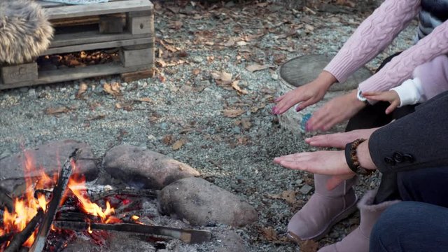 Burning camfire and unidentified women warming hands
