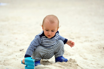 Baby Playing With Sand And Blue Plastic Shovel On The Beach