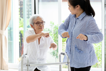 Asian senior people sitting relax with walker during rehabilitation and young carer,elderly woman or mother smiling and exercise with trainer or daughter at home,concept health care