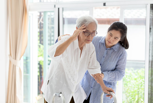 Asian daughter or assistant helping support senior mother,communicates the symptoms of vertigo;dizziness;migraine;sick depressed,suffering from headache,elderly woman in using walker, care concept 