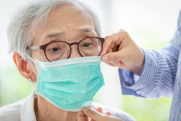 Asian senior woman suffer from cough with face mask protection,elderly woman wearing face mask because of air pollution,Sick old people with medical mask;concept of pollution,dust allergies and health
