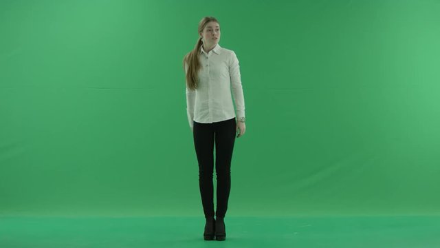a thoughtful woman is waiting and loking at her whatch . She wears formal dress: white shirt and blak trousers. Businesswoman think, got idea over green screen