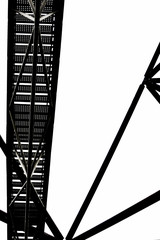 Vertical black and white photo of the staircase and steel construction of Tetrahedron in Bottrop, Germany taken from below against the sky. The popular landmark on a mine dump serves as a view point