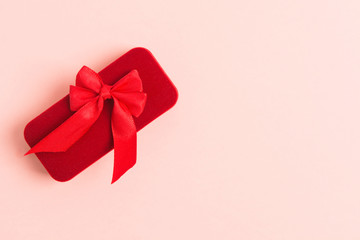 Red jewellery gift box with textile bow over pink background with copy space. Flat lay