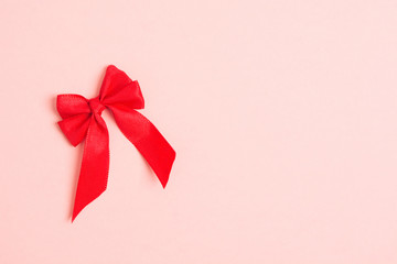 Red textile bow over pink pastel background