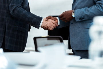 cropped view of african american businessman shaking hands with partner in office