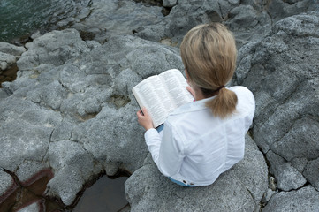 Young mixed race woman reading bible on the river. Beautiful place. Copy space. top view Horizontal...