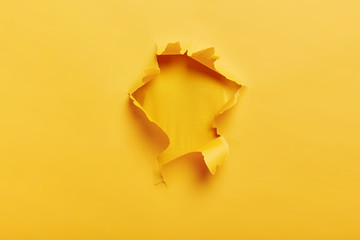 Small paper hole with torn sides over yellow background for your text, print or promotional...