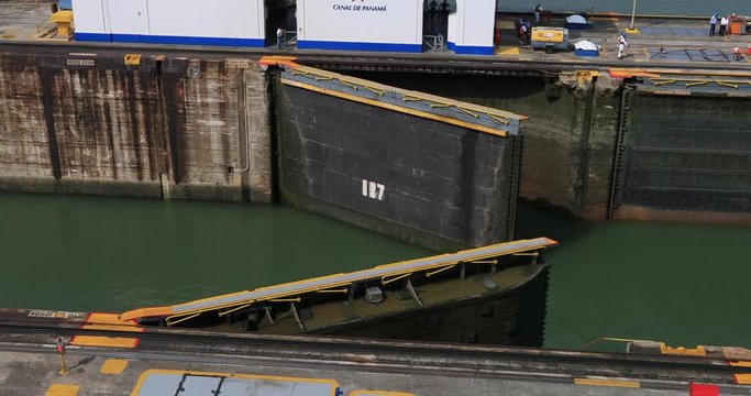 Panama City canal gates closing workers. Lifts a ship between the Atlantic and Pacific Ocean. 52 miles long. Tug boats electric trains pull cargo, cruise, oil, container, bulk, ships. 14,000 ships ann
