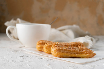morning snack with coffee and creamy eclair on a table with white tablecloth, business breakfasts