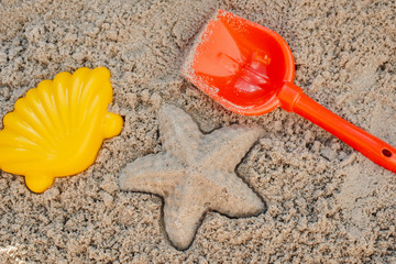 Fototapeta na wymiar Children toys for build the sandcastle, Shovel, Molds laying on the sand at the seashore,