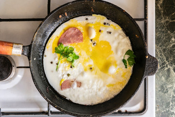 close up process of cooking scpambled eggs in a hot oiled frying pan with pepper and herbss