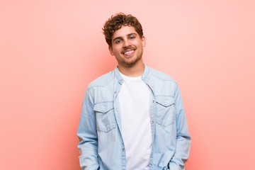 Blonde man over pink wall With happy expression