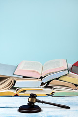 Law concept open book with wooden judges gavel on table in a courtroom or law enforcement office, blue background. Copy space for text.