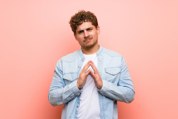 Blonde man over pink wall scheming something