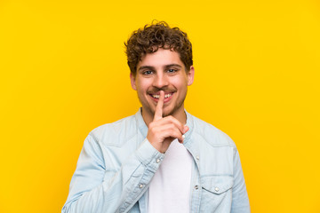 Blonde man over isolated yellow wall doing silence gesture