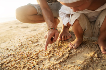 dad and son playing on the sand at the beach at sunset