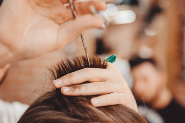 Obraz premium Close-up master hairdresser does hairstyle with scissors and comb. Concept Barbershop