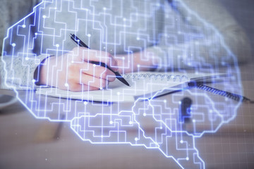 Double exposure of woman's writing hand on background with brain hud. Concept of learning.