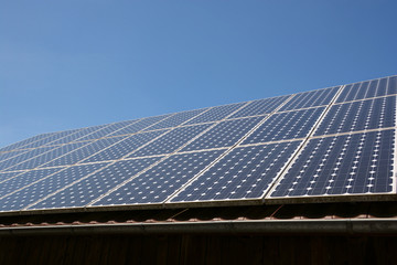 solar panel on roof and sky background, modern solar cells or photovoltaic on the roof of an old woodshed with new gutter in front of azure sky