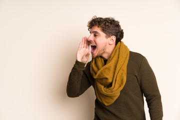 Blonde man with scarf shouting with mouth wide open