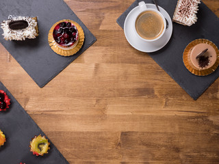 Obraz na płótnie Canvas Top viwe of a cup of coffee with different cakes with different flavours over a wooden table