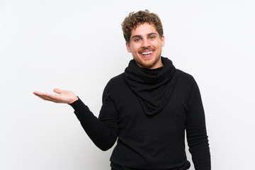 Blonde man over isolated white wall holding copyspace imaginary on the palm to insert an ad