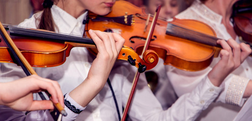 Children play violins during the concert. Performing Classical Music on Violins_