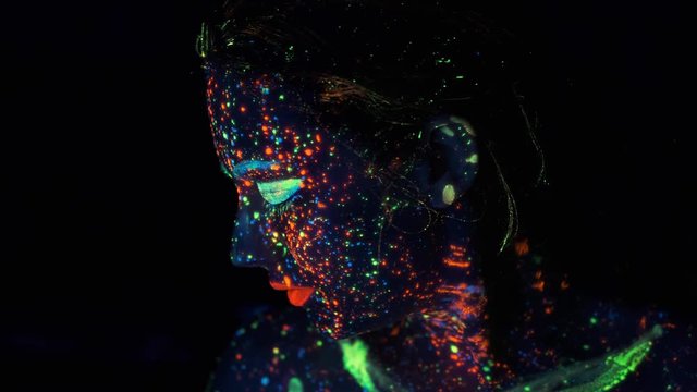 Neon paint on the girl's face. portrait of a young woman painted with luminous paints.
