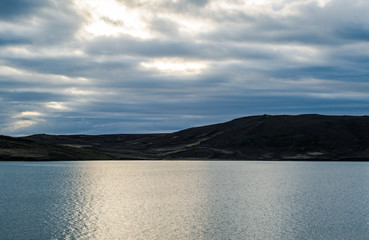 Fantastic view of Iceland in spring. Bright twilight of early white nights over the dreamy landscapes with blue water of the lake and green misty mountains. Splendid view from the lake house