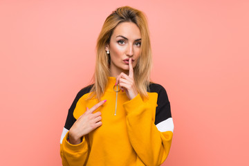 Young blonde woman over isolated pink background showing a sign of silence gesture putting finger in mouth