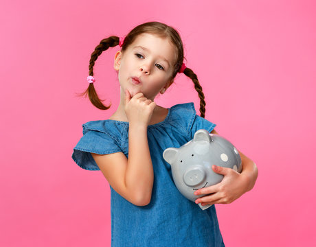 financial concept of children's pocket money. child girl with piggy Bank      on a colored pink background     .