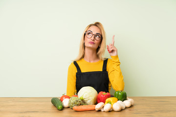 Young blonde woman with lots of vegetables pointing with the index finger a great idea